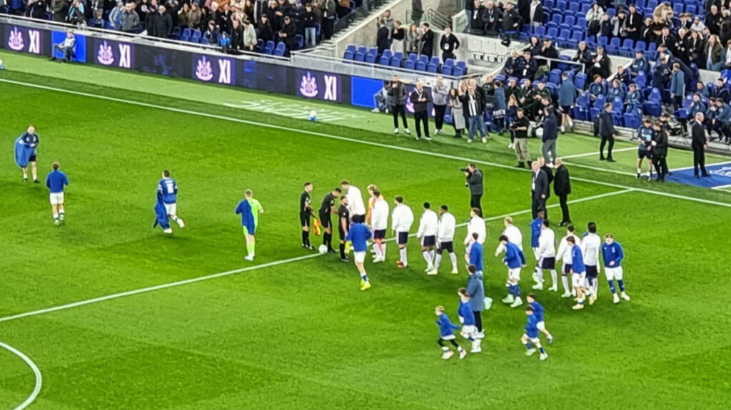Everton and Newcastle United players shaking hands on the pitch ahead of kickoff in the Carabao Cup